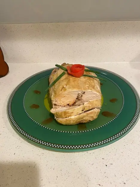 A sandwich on a plate with tomatoes and green onions.