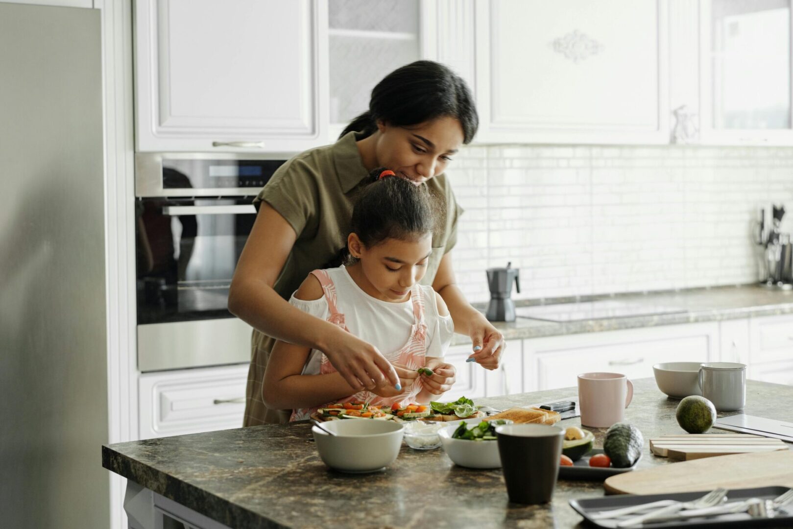 A woman and child in the kitchen preparing food.