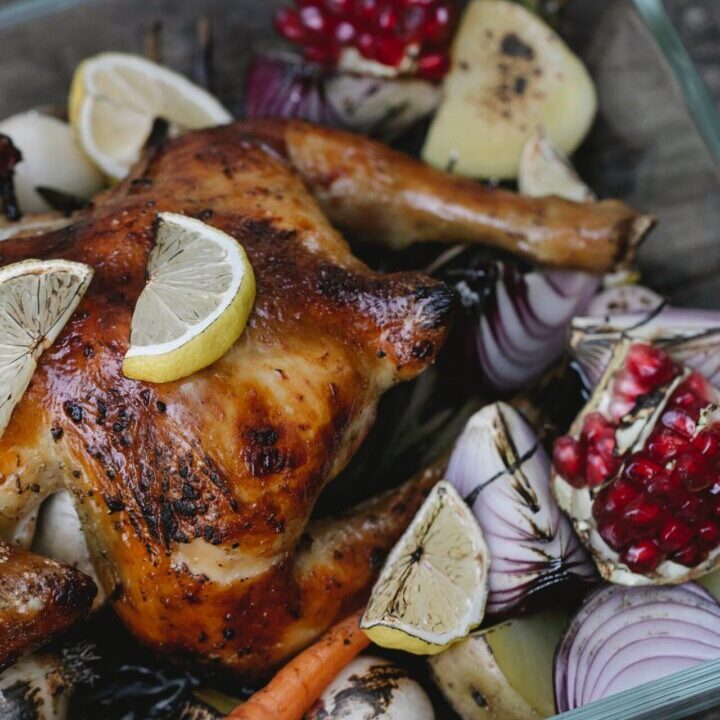 A close up of a chicken with lemon and pomegranate